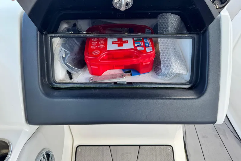 Slide: The Image of Storage compartment on 2023 Hurricane SunDeck 2600 OB with first aid kit and accessories. - 22