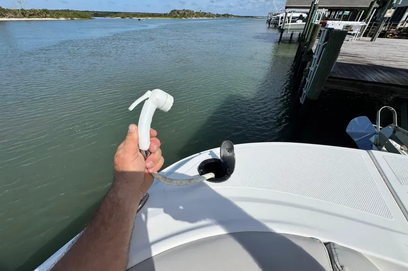 Slide: The Image of Hand holding a hose on a 2023 Hurricane SunDeck 2600 OB boat by the water. - 7