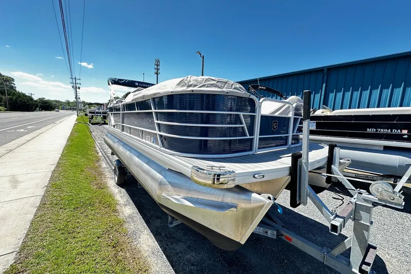 The Image of 2023 Godfrey Sweetwater 2286 SB pontoon boat on trailer, parked roadside under clear blue sky. - 0