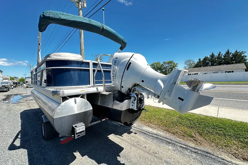 Slide: The Image of 2023 Godfrey Sweetwater 2286 SB pontoon boat with outboard motor, parked on gravel. - 2