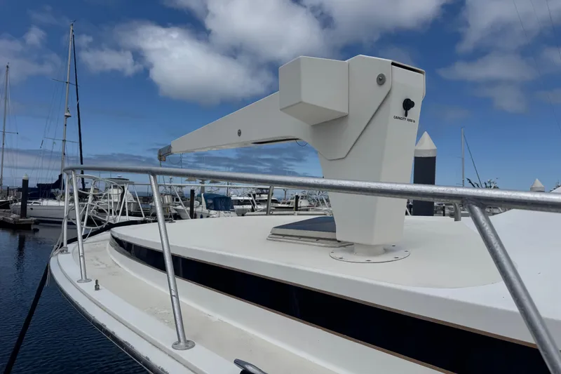 Slide: The Image of 1988 Bertram 50 Convertible yacht with crane, docked at marina under blue sky. - 10