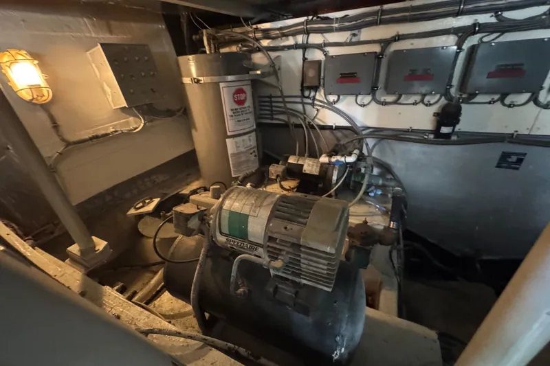 Slide: The Image of Engine room of a 1988 Bertram 50 Convertible boat, featuring machinery and wiring. - 11