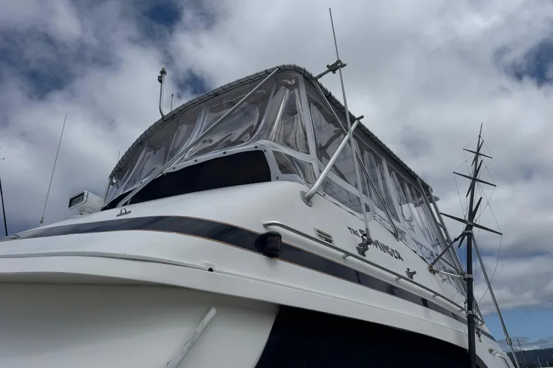 Slide: The Image of 1988 Bertram 50 Convertible yacht with clear enclosure, under cloudy sky. - 12