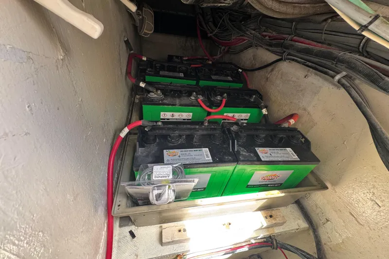 Slide: The Image of Battery compartment of a 1988 Bertram 50 Convertible boat, featuring multiple green batteries. - 25