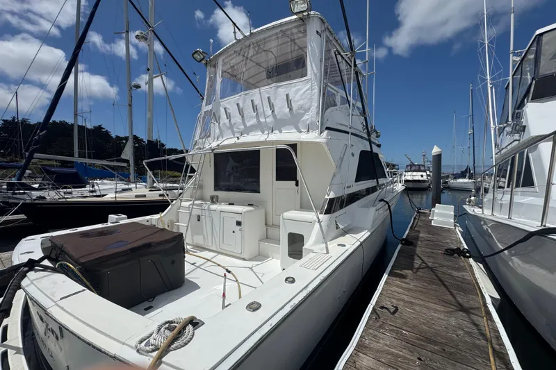 Slide: The Image of 1988 Bertram 50 Convertible yacht docked at marina under clear blue sky. - 3
