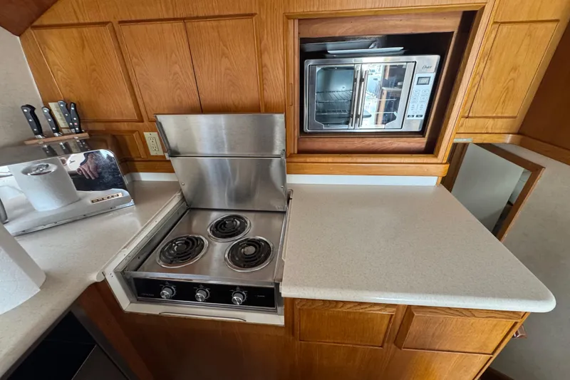 Slide: The Image of Galley kitchen in 1988 Bertram 50 Convertible with stove, microwave, and wooden cabinetry. - 42