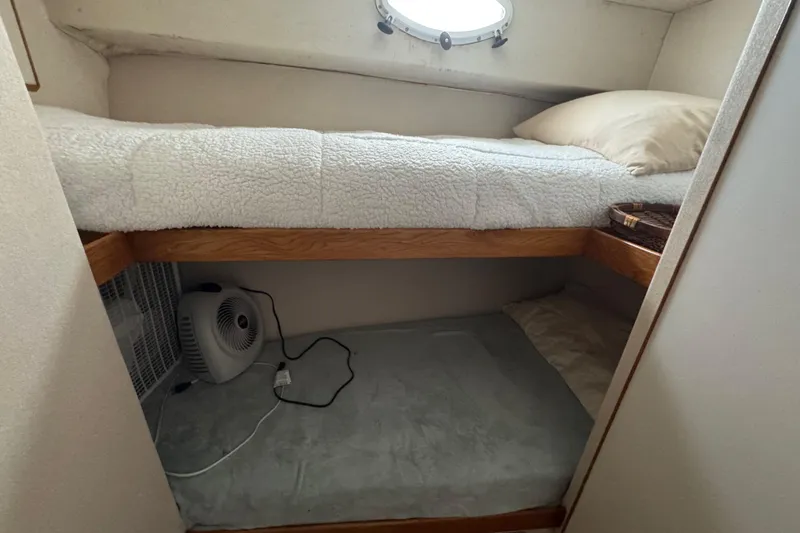 Slide: The Image of Cozy bunk bed in 1988 Bertram 50 Convertible yacht cabin with fan and porthole. - 49