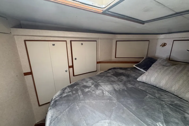 Slide: The Image of Cozy cabin interior of 1988 Bertram 50 Convertible with plush bedding and storage cabinets. - 55