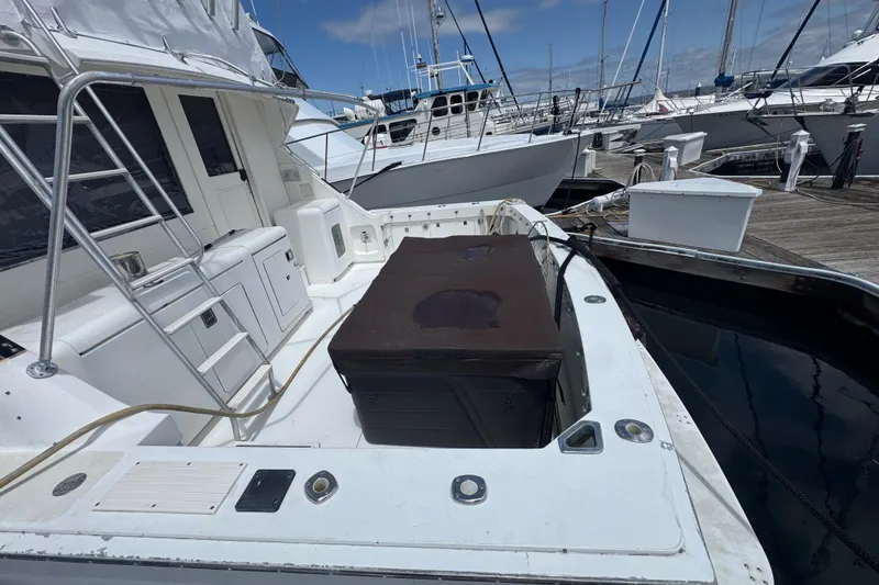Slide: The Image of 1988 Bertram 50 Convertible yacht docked at marina, showcasing spacious deck and sleek design. - 7