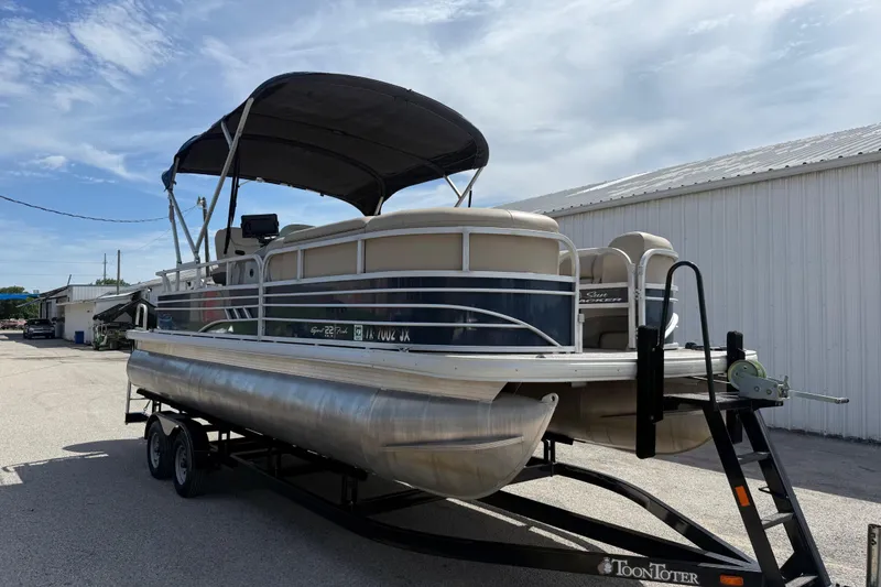 The Image of 2021 Sun Tracker SportFish 22 DLX pontoon boat on trailer, parked outdoors. - 1