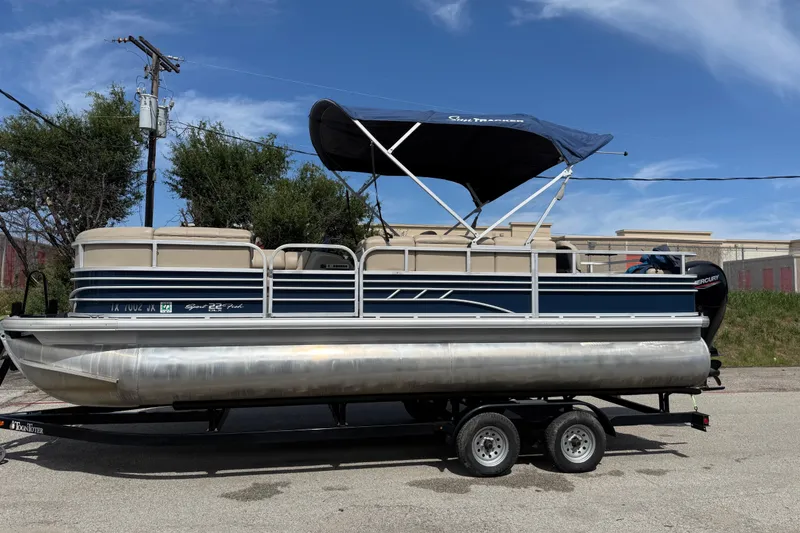 Slide: The Image of 2021 Sun Tracker SportFish 22 DLX pontoon boat on trailer, under blue sky. - 13