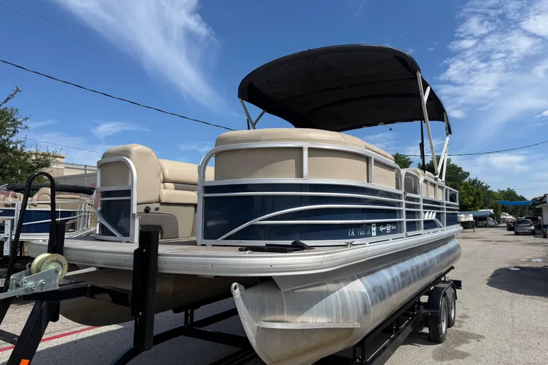 Slide: The Image of 2021 Sun Tracker SportFish 22 DLX pontoon boat on trailer under clear blue sky. - 14