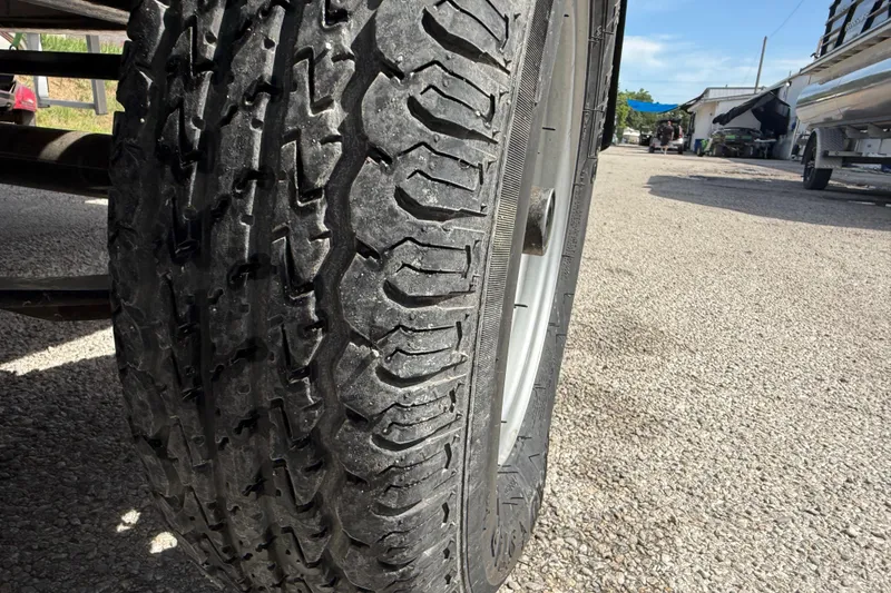 Slide: The Image of Close-up of a 2021 Sun Tracker SportFish 22 DLX trailer tire on gravel. - 19