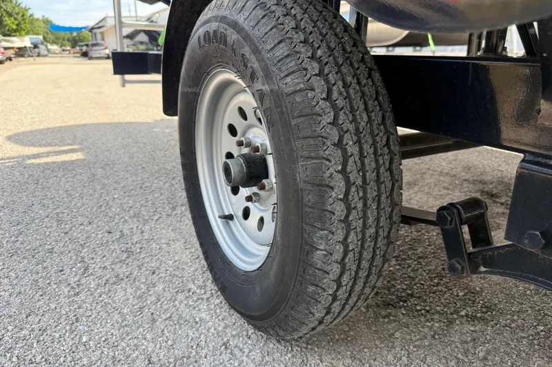 Slide: The Image of Trailer wheel of a 2021 Sun Tracker SportFish 22 DLX on gravel surface. - 22