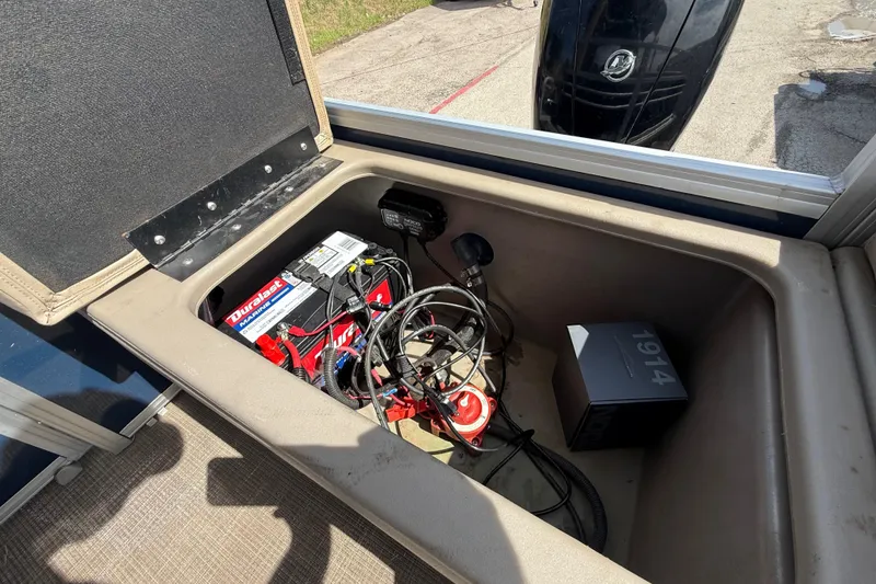Slide: The Image of Open storage compartment in 2021 Sun Tracker SportFish 22 DLX boat, showing battery and cables. - 45
