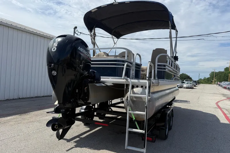 Slide: The Image of 2021 Sun Tracker SportFish 22 DLX pontoon boat with Mercury 150 engine, parked outdoors. - 5