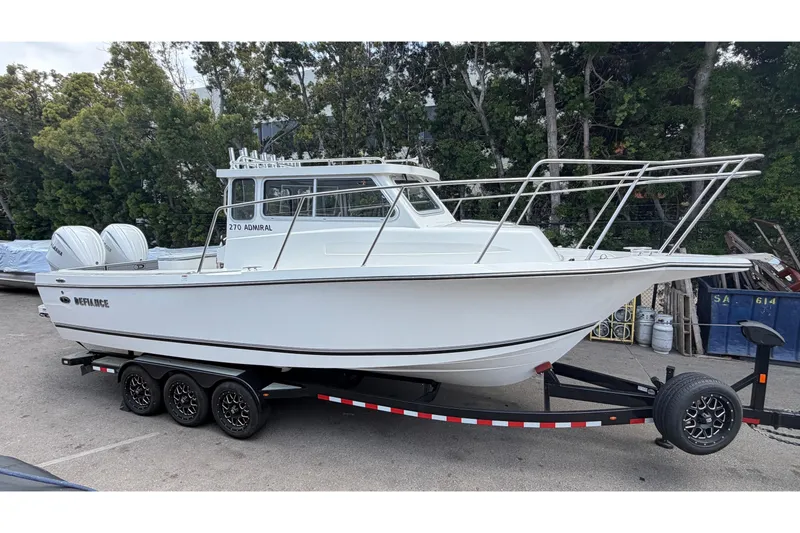 The Image of 2026 Defiance Admiral 270 EX boat on trailer, parked outdoors with trees in background. - 1