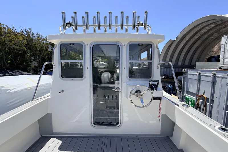Slide: The Image of 2026 Defiance Admiral 270 EX boat cockpit with steering wheel and rod holders. - 24