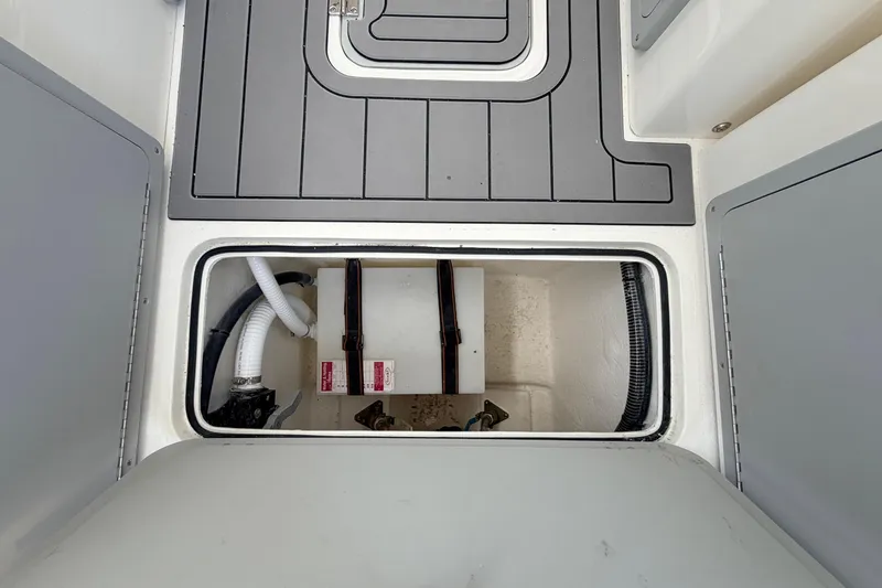 Slide: The Image of Open hatch on 2026 Defiance Admiral 270 EX boat, revealing storage compartment and hoses. - 33