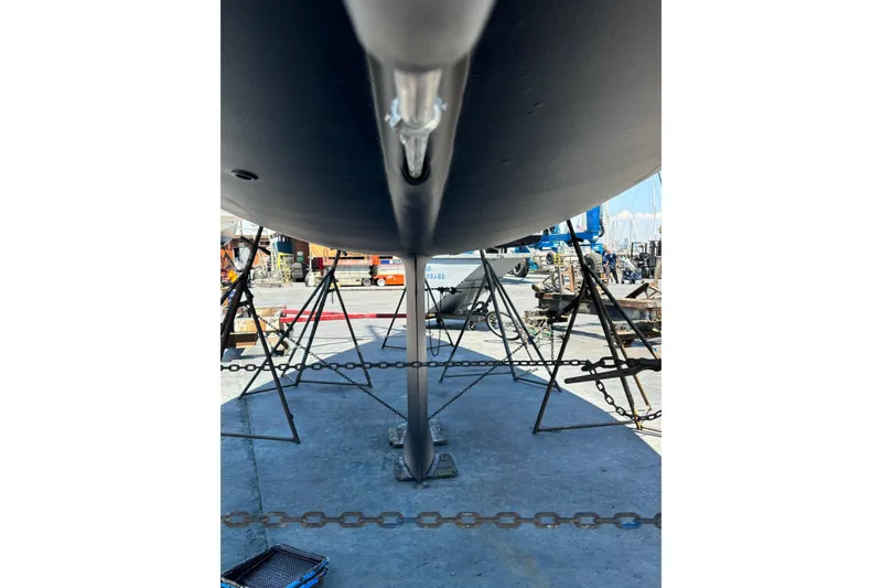 Slide: The Image of Underneath view of a 2002 Sabre 362 sailboat in a shipyard, supported by stands. - 92