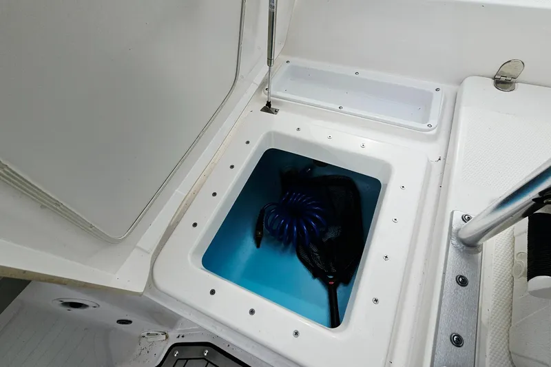 Slide: The Image of 2020 Yamaha Boats 195 FSH Sport storage compartment with coiled hose and net. - 22