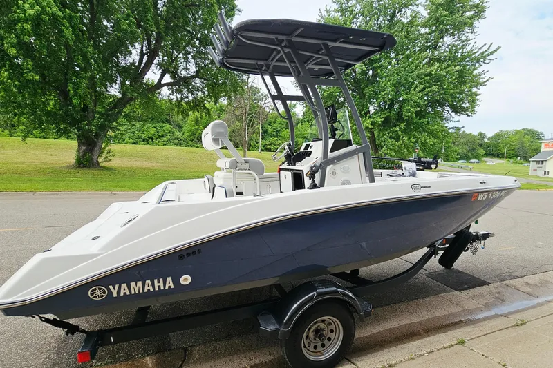 Slide: The Image of 2020 Yamaha Boats 195 FSH Sport on trailer, parked near lush green trees. - 4