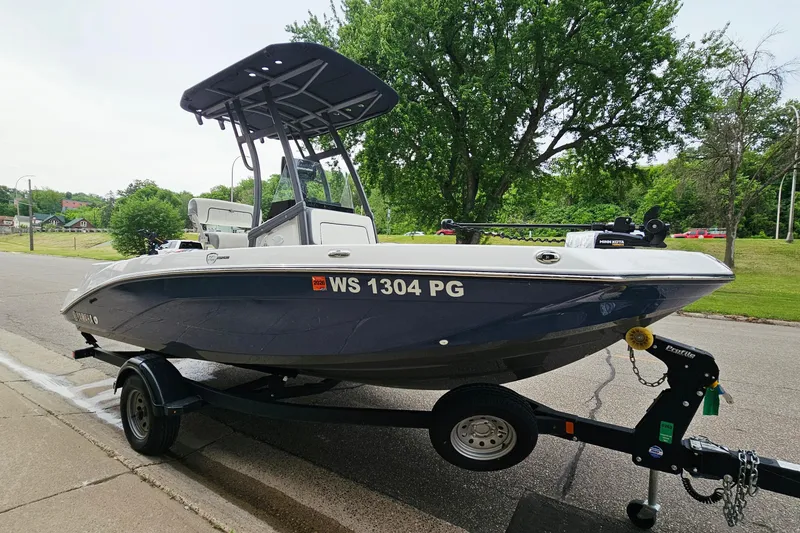 Slide: The Image of 2020 Yamaha Boats 195 FSH Sport on trailer, parked roadside with lush greenery background. - 5