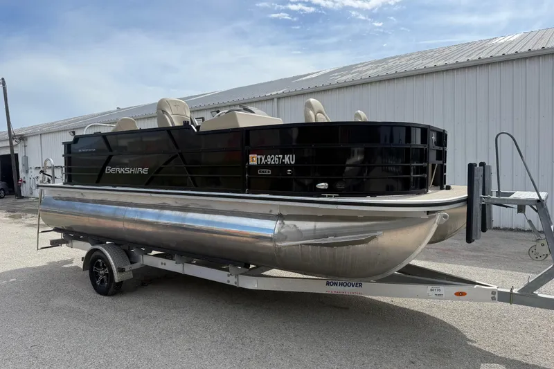 Slide: The Image of 2023 Berkshire 20A CTS pontoon boat on trailer, parked near a metal building. - 17