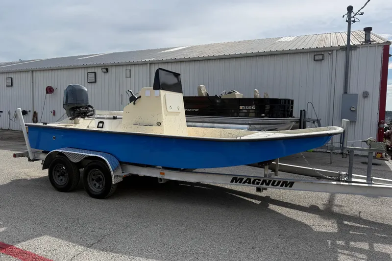 Slide: The Image of 2007 Flats Cat 19 boat on Magnum trailer, parked outside a metal building. - 11