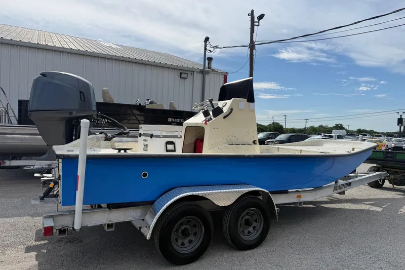 Slide: The Image of 2007 Flats Cat 19 boat on trailer, blue hull, parked outdoors near a metal building. - 13