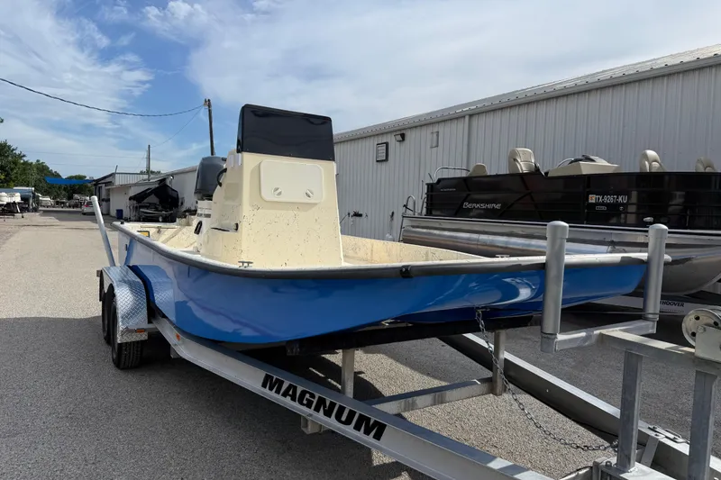 Slide: The Image of 2007 Flats Cat 19 boat on trailer, blue hull, parked outdoors near other boats. - 8