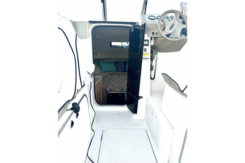 Slide: The Image of 2000 Bayliner 2252 Ciera Express cabin interior with steering wheel and cozy sleeping area. - 24