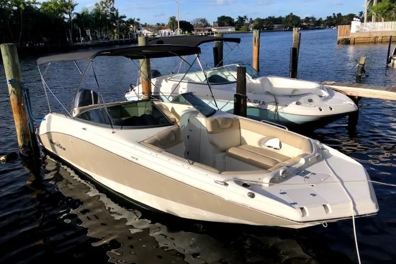The Image of 2017 NauticStar 243DC Sport Deck boat docked on a sunny waterfront. - 0