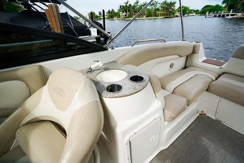 Slide: The Image of 2017 NauticStar 243DC Sport Deck interior with beige seating and cup holders by the water. - 12