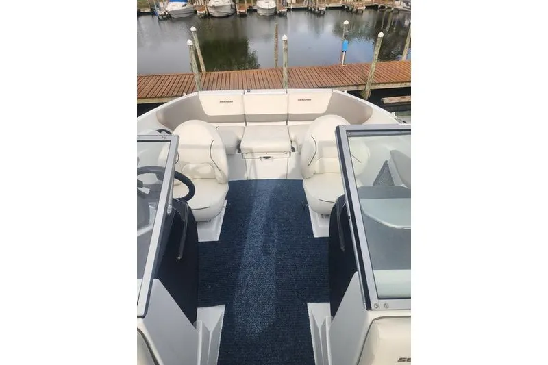 Slide: The Image of 2012 Sea-Doo Sport Boats 180 Challenger interior with seating and steering, docked by the water. - 15