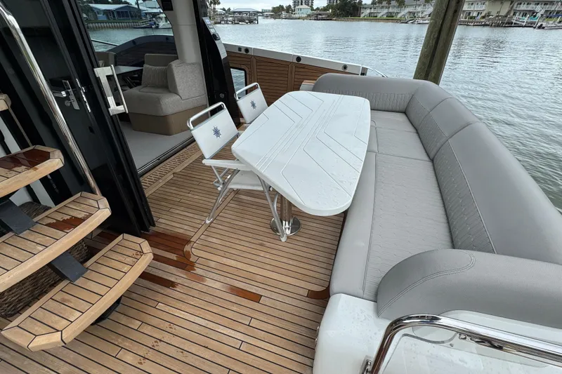 Slide: The Image of Luxurious 2024 Galeon 560 Fly yacht deck with seating and table, overlooking serene waters. - 58