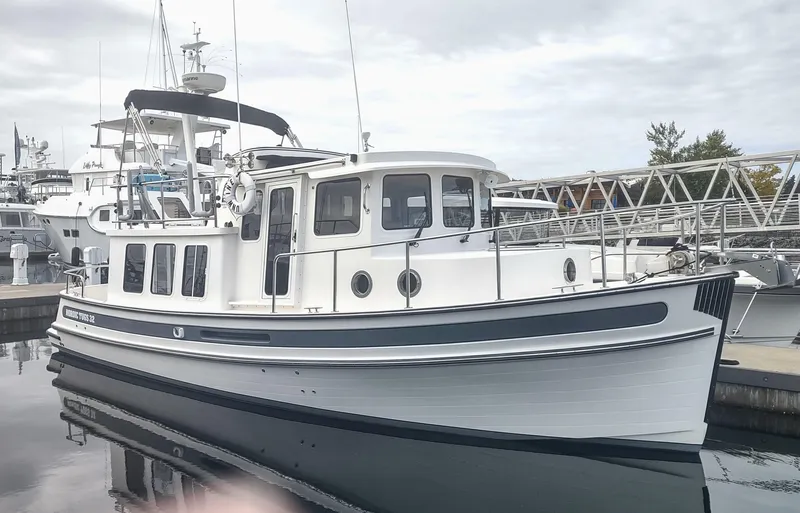 The Image of 2005 Nordic Tug 32 docked, white boat with blue accents. - 0