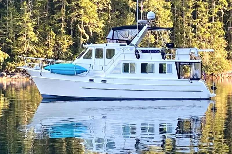 The Image of 2006 North Pacific 42 Pilothouse yacht on calm water, surrounded by lush forest. - 0