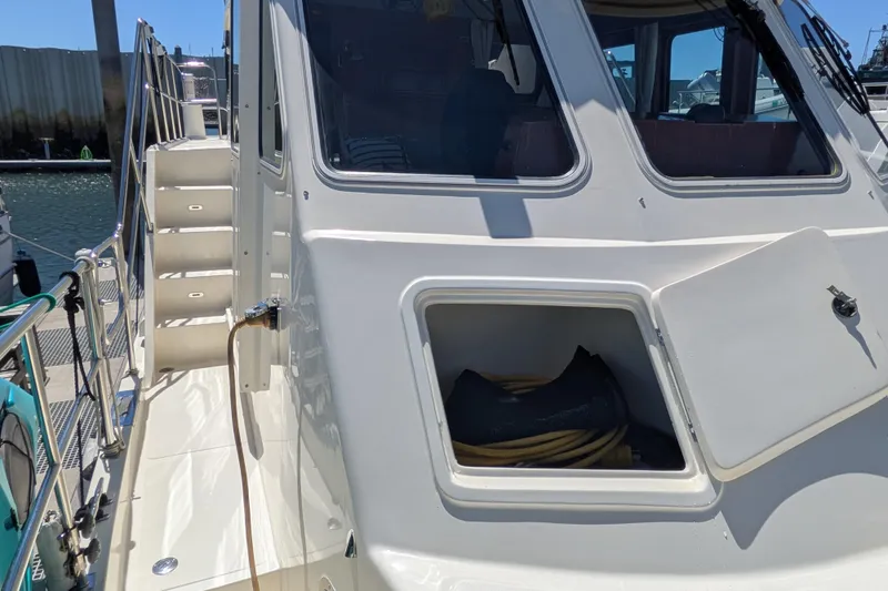 Slide: The Image of 2006 North Pacific 42 Pilothouse yacht with open storage compartment and dockside view. - 12