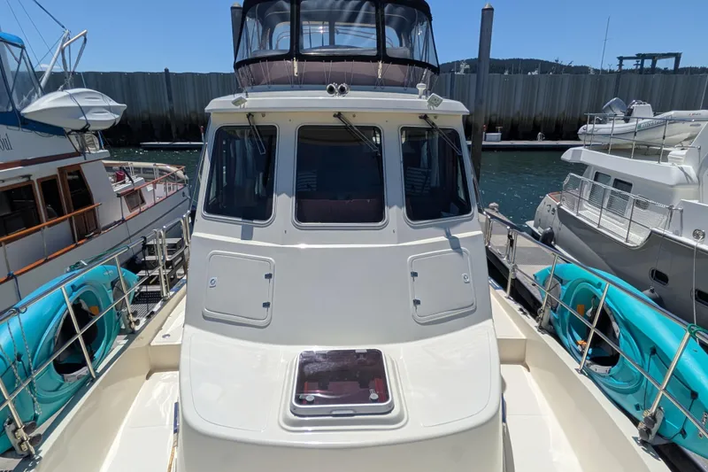 Slide: The Image of 2006 North Pacific 42 Pilothouse yacht docked, featuring spacious deck and pilothouse windows. - 13