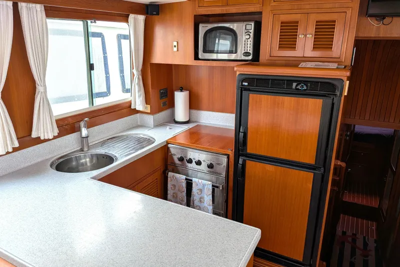 Slide: The Image of Kitchen area of a 2006 North Pacific 42 Pilothouse with wood cabinetry and modern appliances. - 23