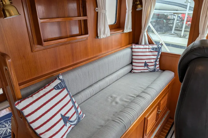 Slide: The Image of Cozy interior of 2006 North Pacific 42 Pilothouse with nautical-themed cushions and wooden cabinetry. - 29