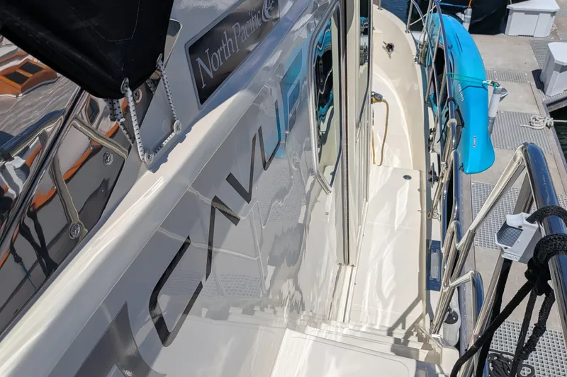 Slide: The Image of 2006 North Pacific 42 Pilothouse yacht docked, featuring sleek design and vibrant blue kayak. - 8