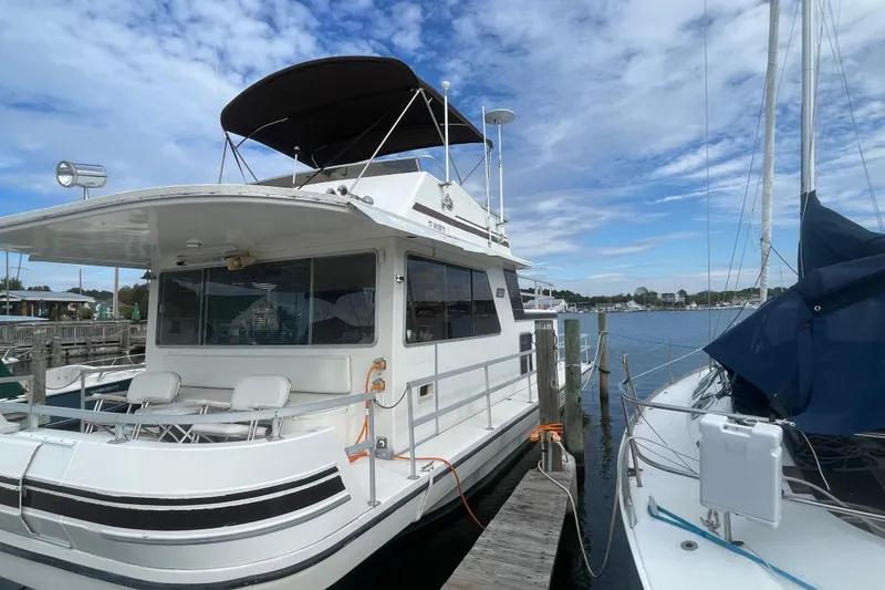 Slide: The Image of 1991 Gibson 37 Standard Houseboat docked at marina under blue sky. - 1
