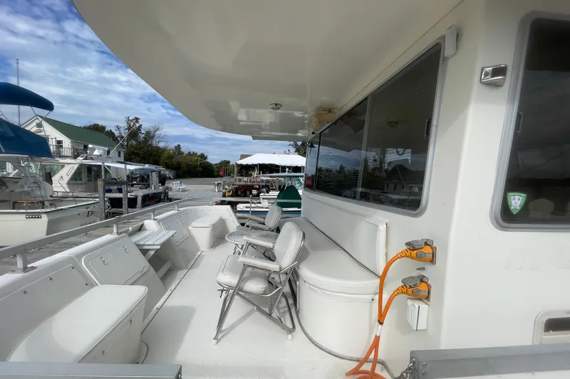 Slide: The Image of 1991 Gibson 37 Standard Houseboat with seating area, docked at marina under cloudy sky. - 18