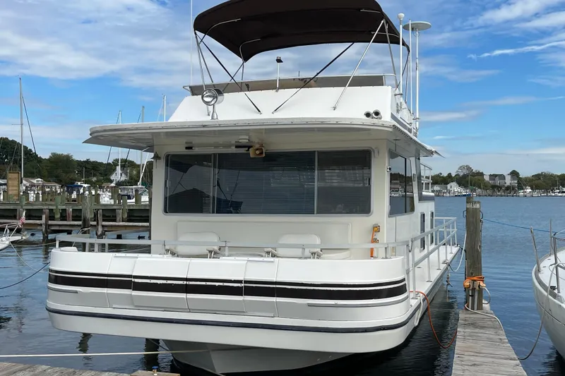 Slide: The Image of 1991 Gibson 37 Standard Houseboat docked at a marina under a clear blue sky. - 2