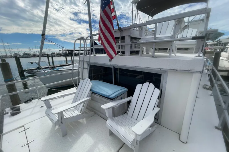 Slide: The Image of 1991 Gibson 37 Standard Houseboat with deck chairs and American flag at marina. - 20
