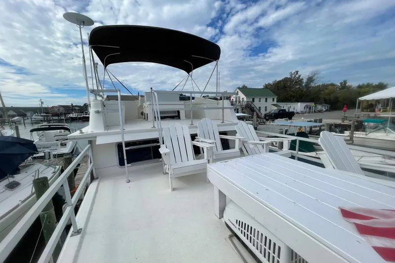 Slide: The Image of 1991 Gibson 37 Standard Houseboat with deck chairs and canopy at marina. - 22