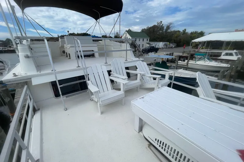 Slide: The Image of 1991 Gibson 37 Standard Houseboat with spacious deck and white Adirondack chairs. - 23
