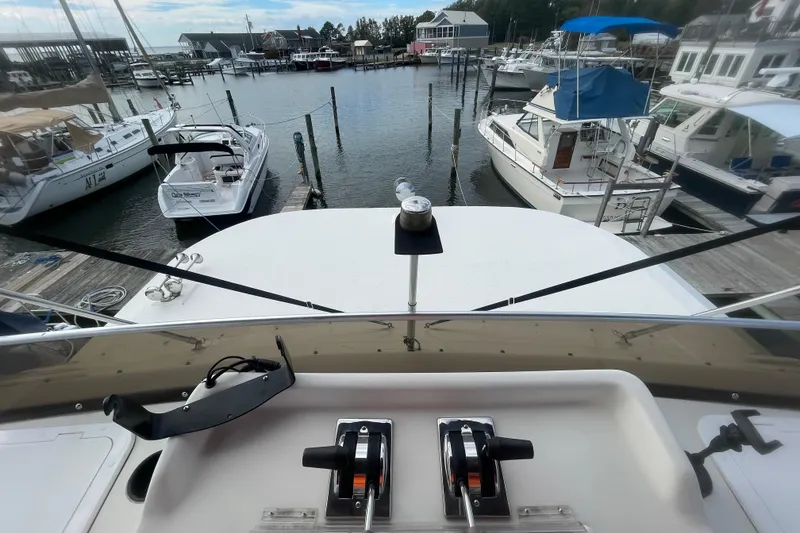 Slide: The Image of View from a 1991 Gibson 37 Standard Houseboat docked at a marina, showing controls and surrounding boats. - 27